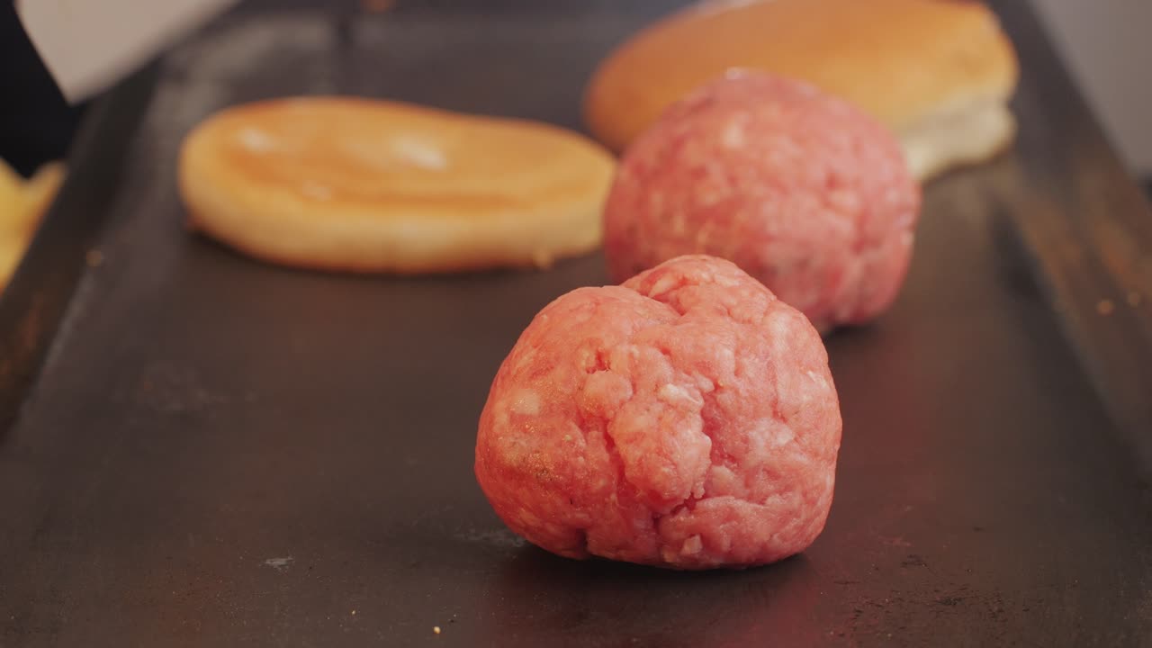 Cooking American fat smash burger on grill close-up. Beef or pork cutlet smashing by burger press. The chef in kitchen of the restaurant making cutlets for burgers - smash burger beefsteak. Fast and street food concept. High quality 4k footage