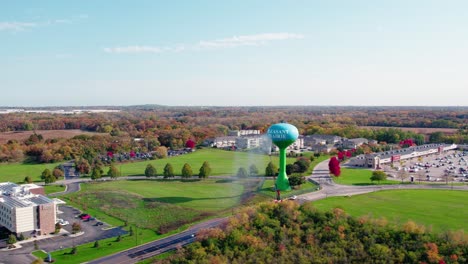 Service-truck-power-washes-a-water-tower,-ensuring-clean-supply-amid-a-verdant-suburban-setting