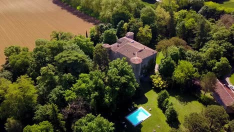 Vista-Aérea-Del-Castillo-Medieval-Enclavado-En-árboles-Cerca-De-Una-Gran-Granja-Agrícola