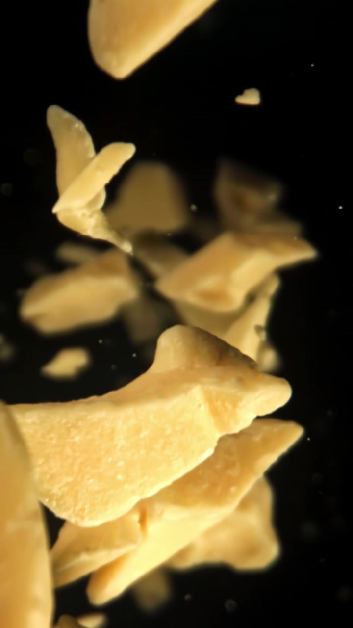 Cocoa Butter Pieces Falling in Slow Motion on Black Background