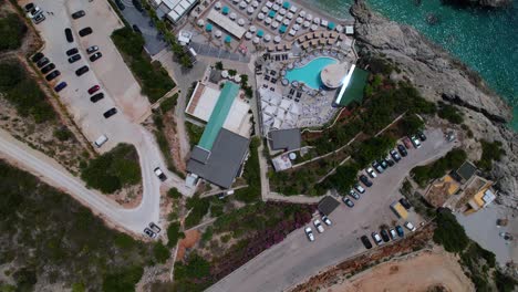 Holiday-resort-with-pool,-parking-and-beach-chairs-near-blue-turquoise-sea-water-in-Albania