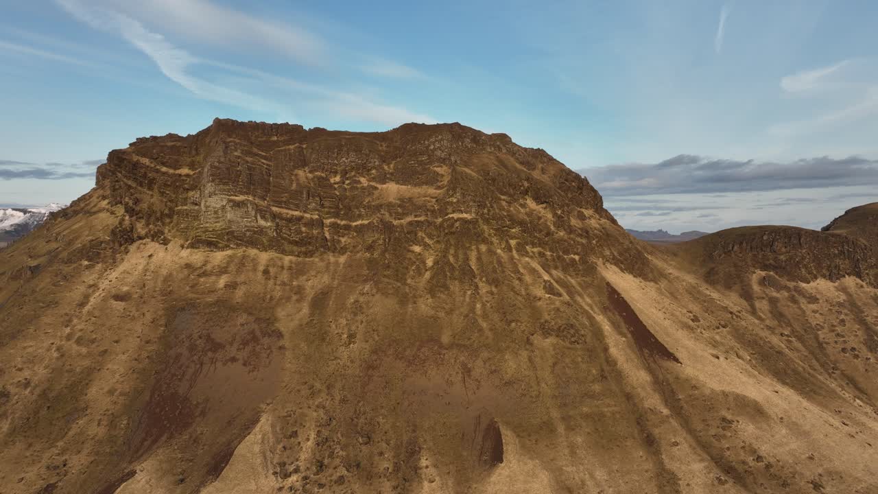 아이슬란드 부르펠 (búrfell) 에 있는 웅장하고 험한 산의 드론 촬영으로, 은 하늘 아래의 극적인 바위 형성과 황량한 지형을 보여줍니다.