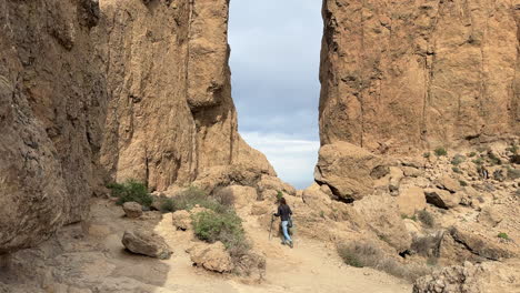tourist walking in a desert landscape towards roque nublo, volcanic rock in gran canaria, canary islands