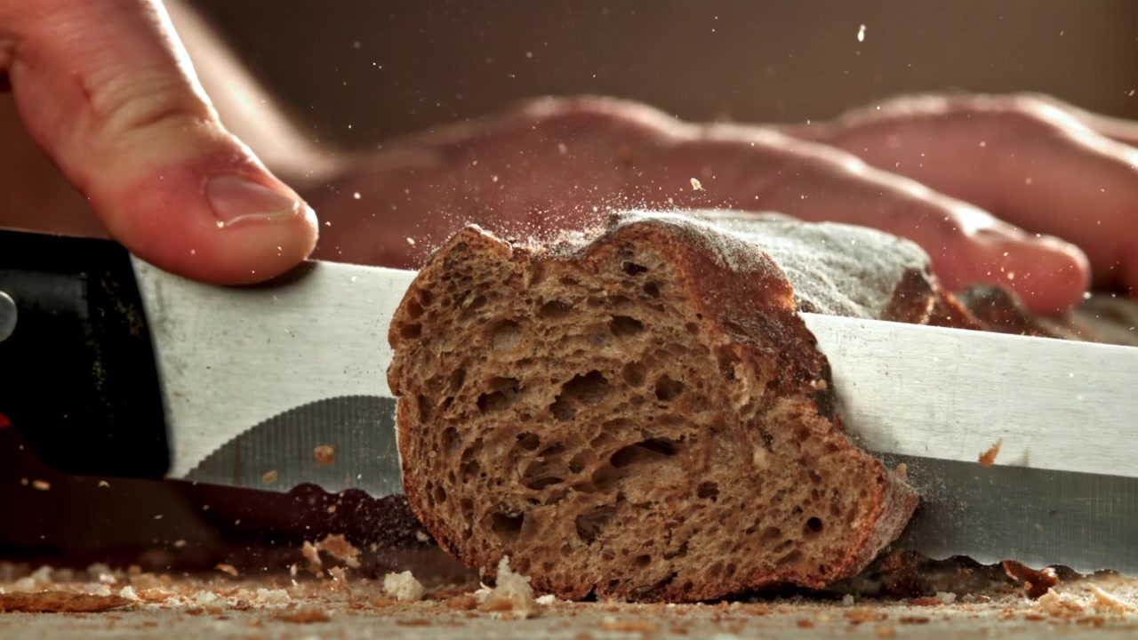 Slicing Fresh Rustic Bread with a Serrated Knife in Slow Motion