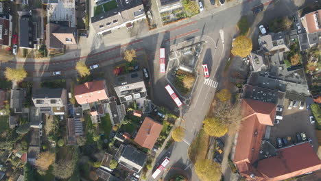 Antena-De-Arriba-Hacia-Abajo-De-Autobuses-Que-Salen-De-Una-Pequeña-Estación-De-Autobuses-En-Un-Pequeño-Pueblo-En-Otoño