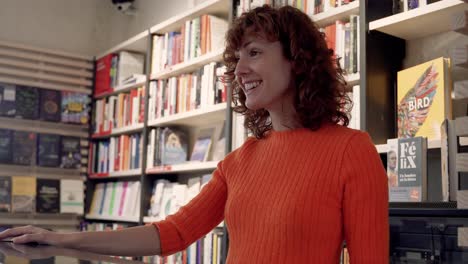 young attractive curly brunette woman talking with a smile at bookshop