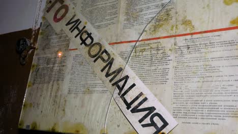 old information board with russian text inside the abandoned soviet underground bomb shelter, old soviet cold war bunker, apocalypse, medium handheld shot