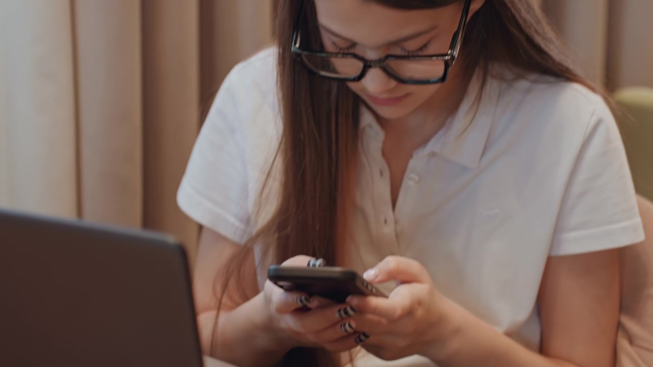 Una persona interagisce con il telefono e il laptop. Un individuo esamina i messaggi usando il telefono e il computer. Primo piano di una persona che utilizza sia lo smartphone che il laptop per attività di messaggistica e ricerca a casa.