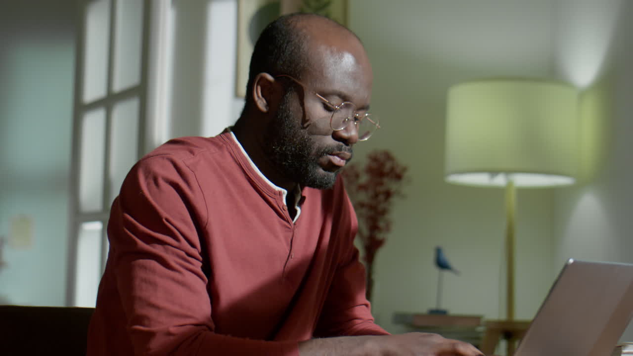 African American Man Typing on Laptop in Evening at Home