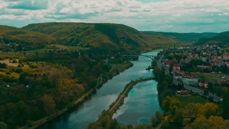 Vista-Aérea-Del-Pueblo-Al-Lado-Del-Río-En-Europa-Fuera-De-Praga-Bajo-Las-Nubes-Y-La-Luz-Del-Sol