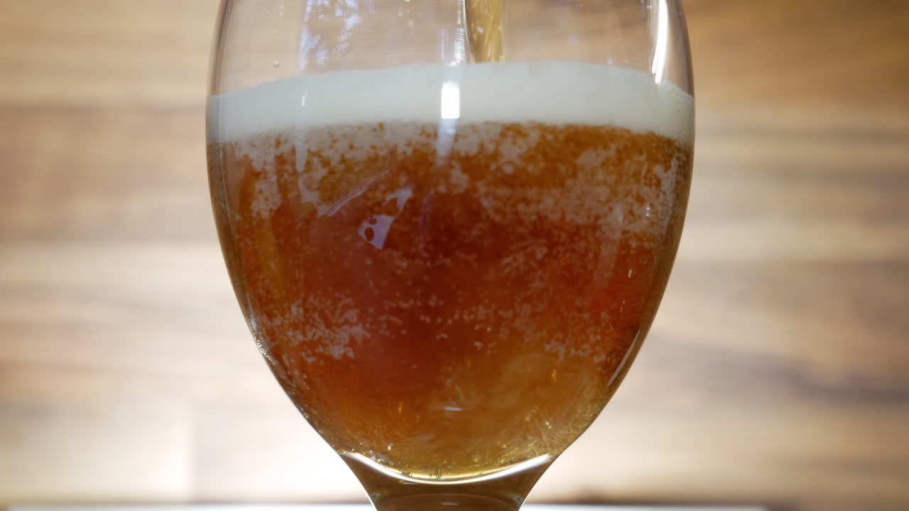 Pouring fresh and tasty dark beer into glass, close up view