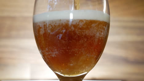 pouring fresh and tasty dark beer into glass, close up view