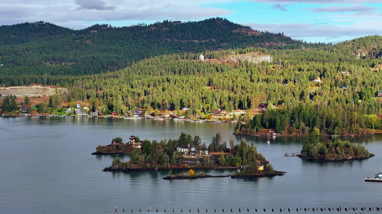 Aerial overview of small forested islands and lakeside homes on Flathead Lake Montana under clear sky