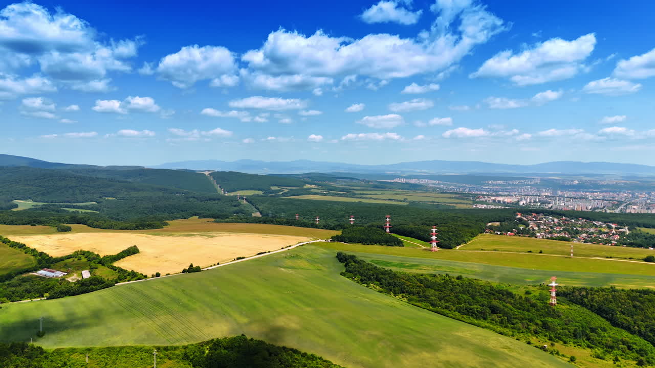 European countryside vista. Aerial view showcases rolling hills, fields, and distant mountains under a clear blue sky in Europe