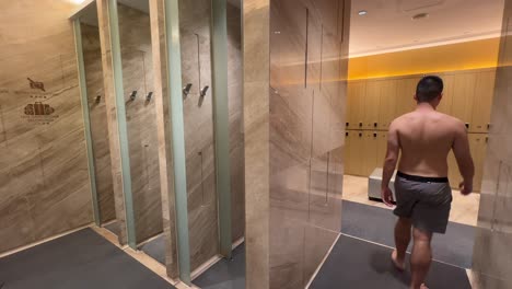 hombre asiático del milenio saliendo de la ducha en un lujoso vestuario de lujo