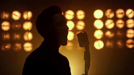 Silhouette-singing-man-vocalist-using-microphone-on-show-stage-nightclub-closeup
