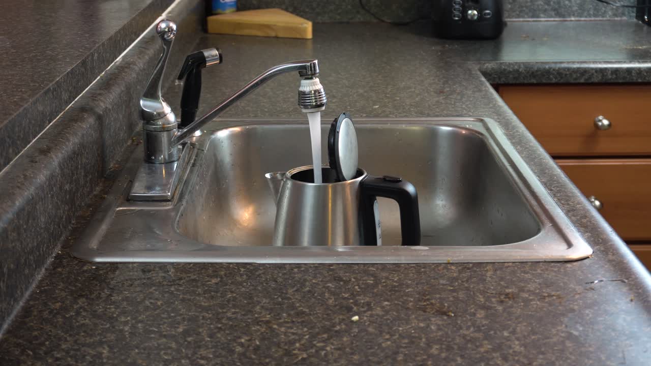 やかんに水を注ぐ個人のミディアムショット