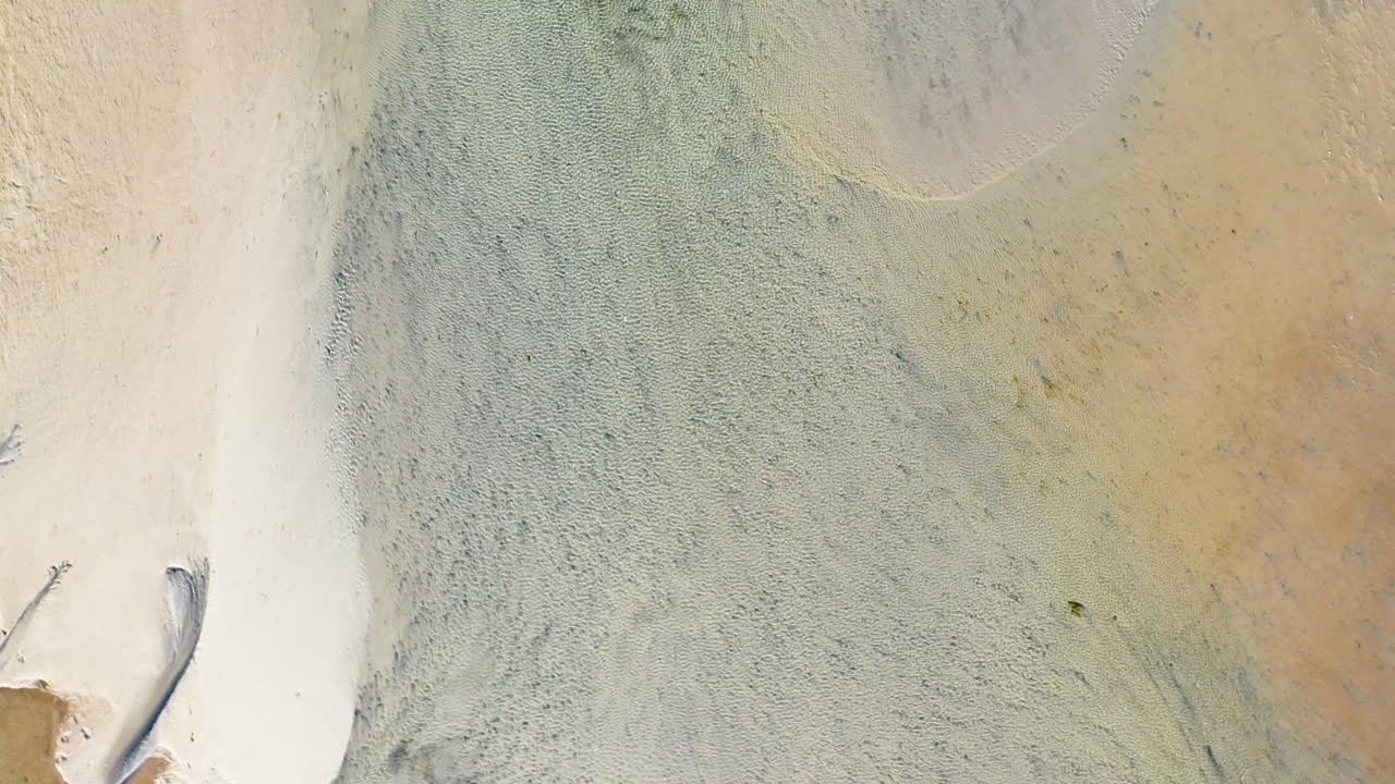 바람에 파도가 부는 얕은 바다 해변과 모래의 드론 공중 상승 및 스핀 공개