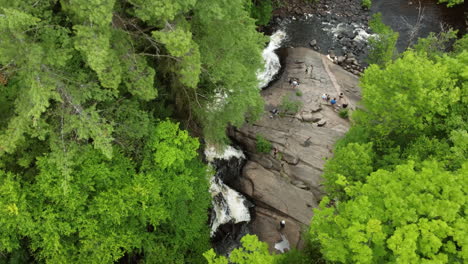 birds eye view drone fly around arrowhead provincial park capturing beautiful stubb’s falls with people resting on rock, enjoying the pleasant natural environment, huntsville, ontario, canada