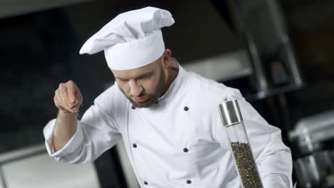 retrato de un hombre cocinero salando comida en la cocina. cocinero concentrado cocinando comida