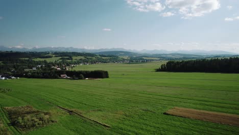 Toma-Aérea-De-4k-De-Las-Montañas-Tatra,-Campos-Verdes-Y-Campos-En-Un-Día-Soleado