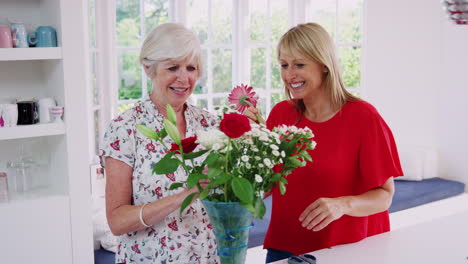 Ältere-Frau-Und-Erwachsene-Tochter-Arrangieren-Blumen-In-Der-Küche