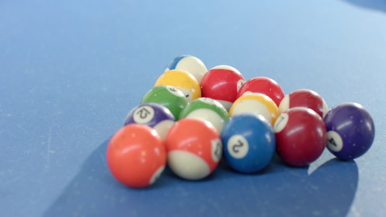 Camera is moving back tilting up, revealing rack of billiard balls on blue pool table