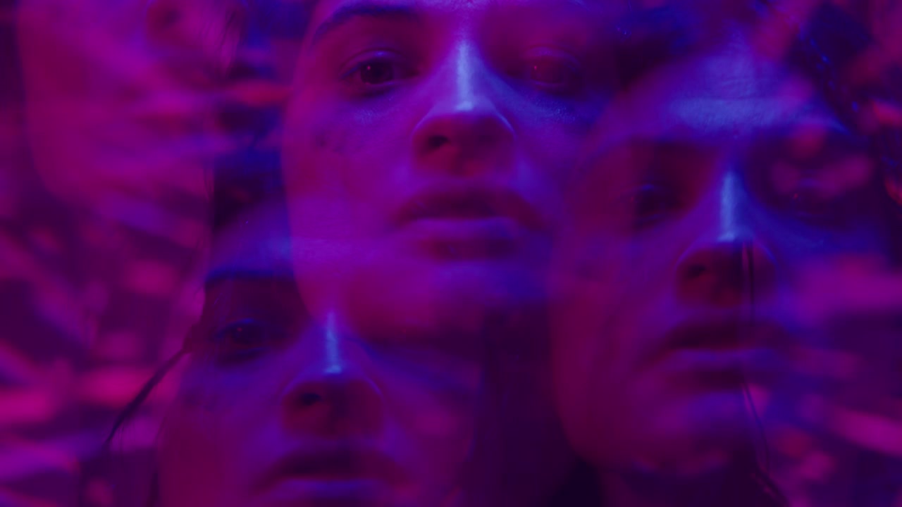 Effet kaléidoscope d'une femme au mascara coulé sous une lumière néon