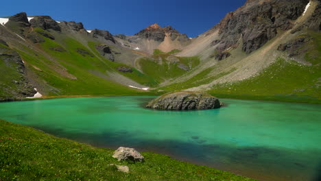 paraíso cinematográfico aéreo cuenca del lago de hielo isla de silverton lago aqua azul agua clara tundra alpina impresionante cordillera flores silvestres mediados del verano durante el día bluesy hermoso movimiento lento hacia la izquierda