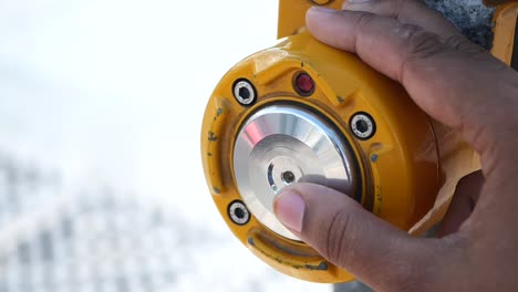 close-up of a hand pushing a yellow button on a control panel