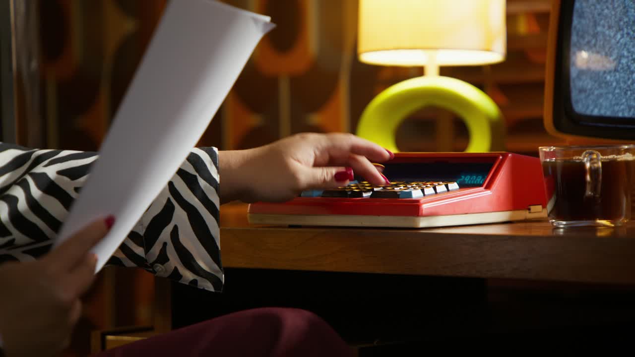 Woman working at a vintage desk with calculator
