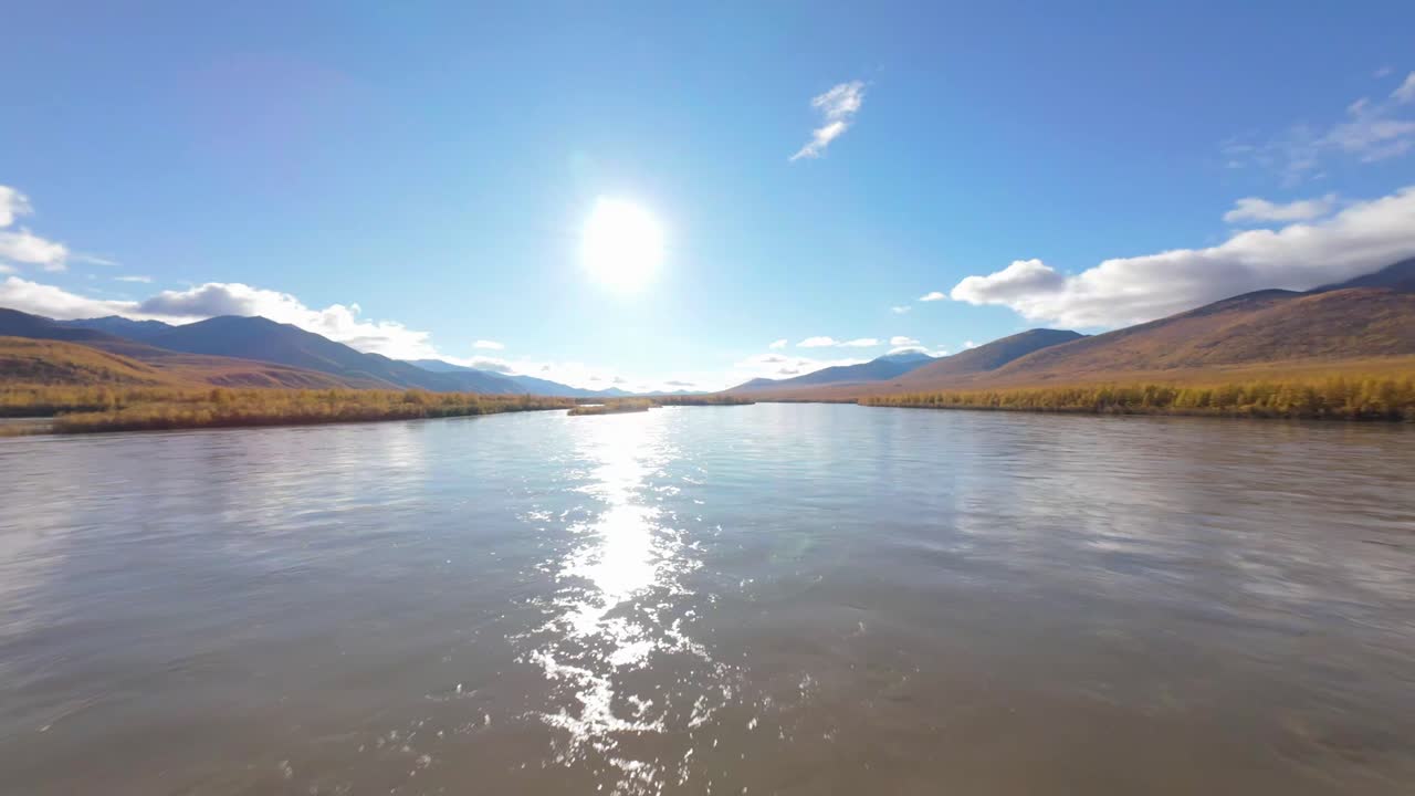 Experience the stunning beauty of nature as vibrant autumn colors surround a tranquil river, illuminated by the warm glow of the setting sun. Peaceful and picturesque, this moment captures serenity.