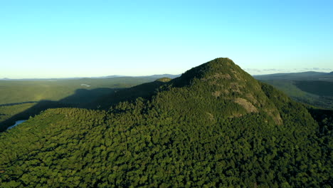 Aerial-drone-shot-of-Bore-Mountain-revealing-a-blue-lake-in-the-shadow-of-the-peak-among-the-thick-green-forest-of-the-Maine-wilderness