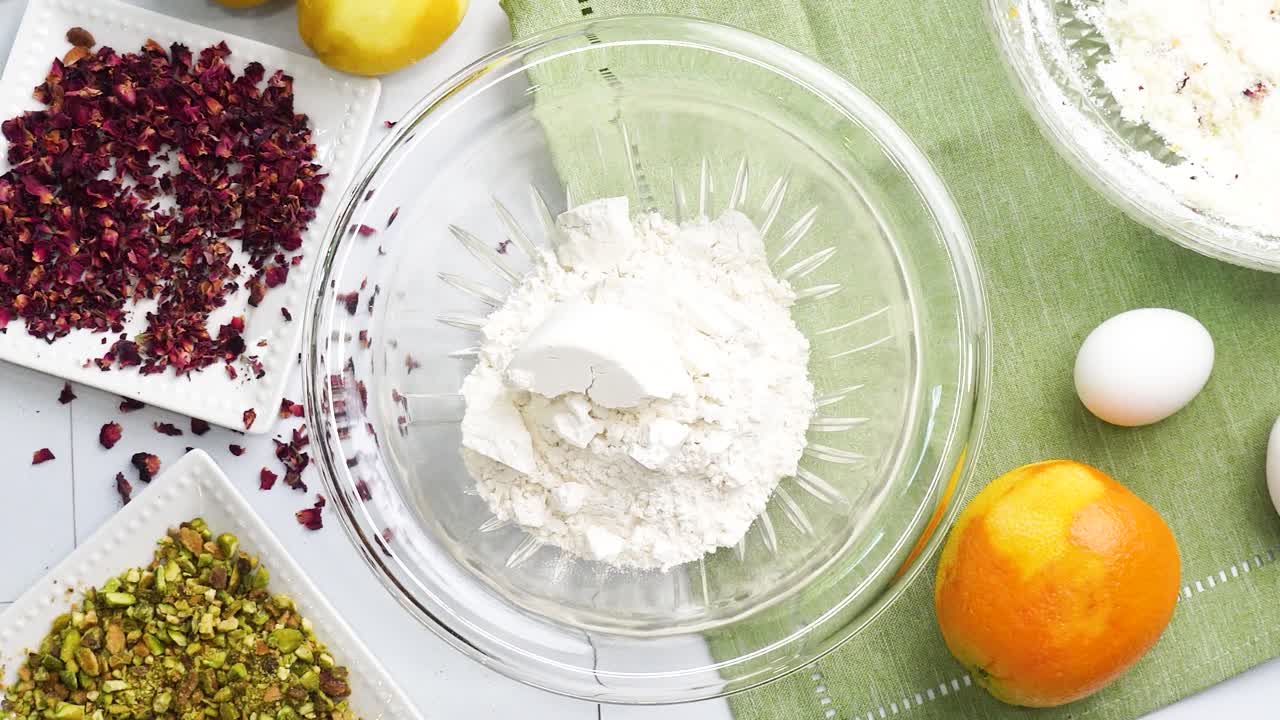Baking a dessert called Persian Love Cake made with rose petals and pistachios. Cake with white glaze frosting. Mixing in the almond flour to the batter. Beautiful cake for tea time or celebration