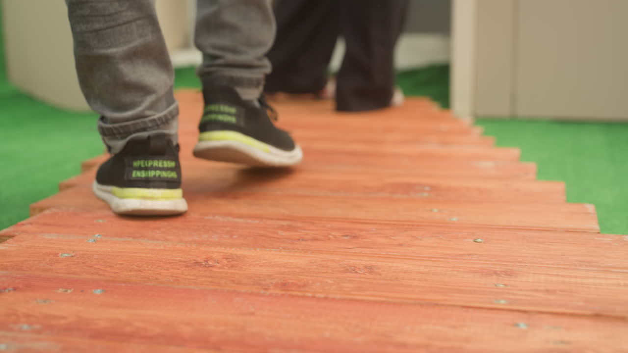 closeup feet walking wooden path intimate date stroll on staged green turf set with alternating sneakers and heels textured planks underfoot slow rhythmic steps candid lifestyle vibe modern casual