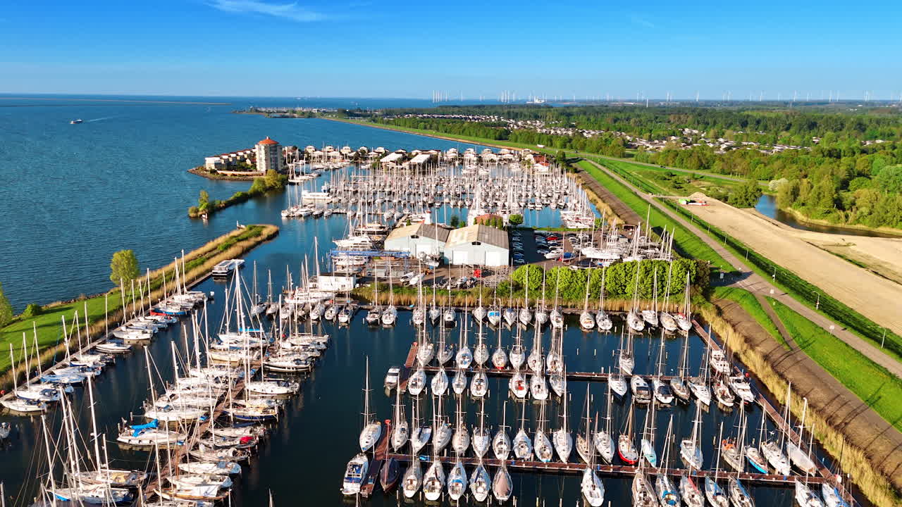 Multiple yachts in the yacht club on the Markemeer in Lelystad, the Netherlands. Beautiful lakefront with lush greenery at backdrop. Aerial view.