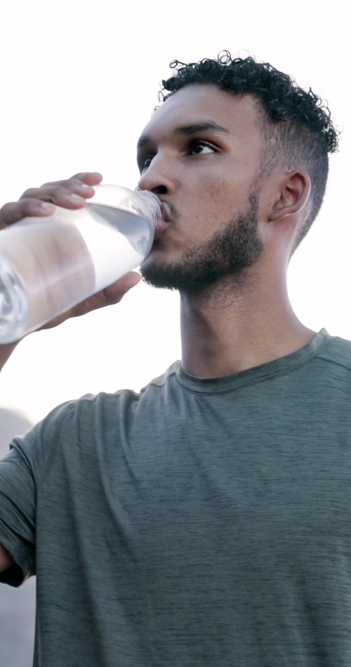Young Man Drinking Water from a Bottle Outdoors