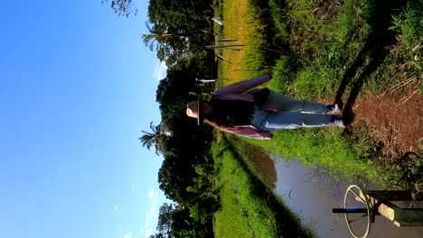 mujer caminando junto a una zanja de riego a través de campos de arroz