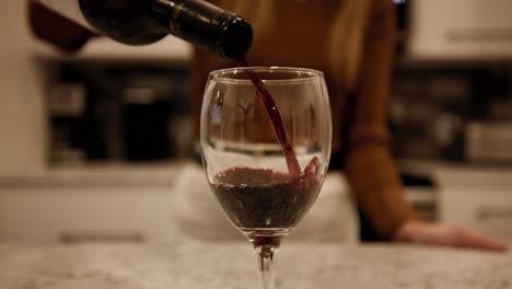 closeup of a wineglass with red wine pouring