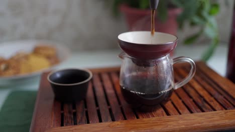 tea ceremony on a portable table. brewed tea is transferred through a funnel into an empty teapot, saturated with oxygen and revealing the taste of tea