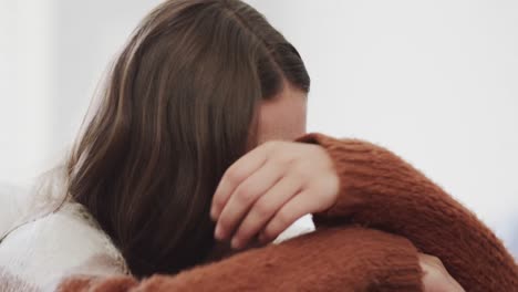 sad caucasian teenage girl sitting on bed and covering her face