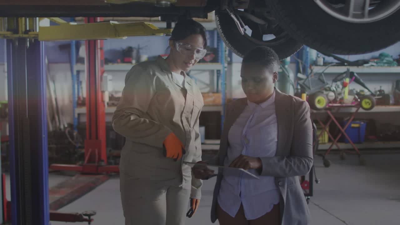 Mechanic and manager reviewing tablet under lift analyzing AR diagnostics on vehicle for inspection