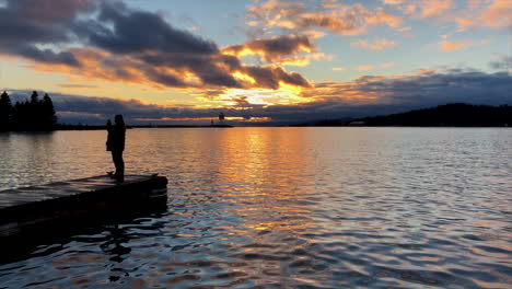 mujer tomando fotos de la puesta de sol en el lago superior