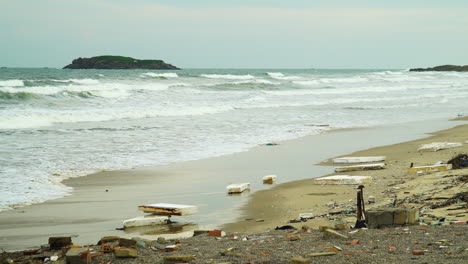 styrofoam trash pollution on beach as ocean waves roll into shore on gloomy day