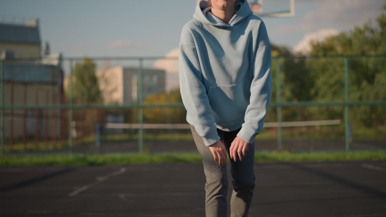 푸른 스웨터를 입은 여자가 야외에서 피트니스 운동을 하며, 밝은 배경과 평온한 분위기 속에서 법정에서 무을 고 스트레칭을 합니다.