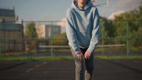 lady in blue sweater engaging in fitness exercise outdoors, performing kneeling stretch in court with bright background and calm atmosphere