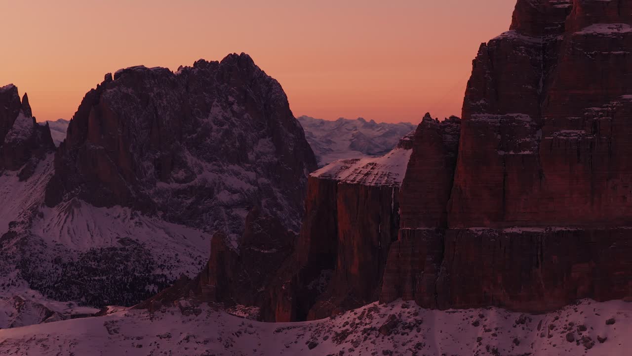 Kæmpe massiver og lodrette vægge i en stor sneklædt dal i Dolomitterne.