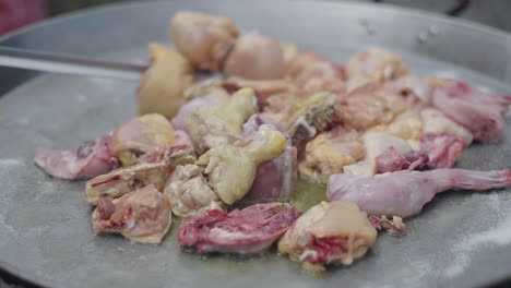 raw chicken pieces cooking in a large pan