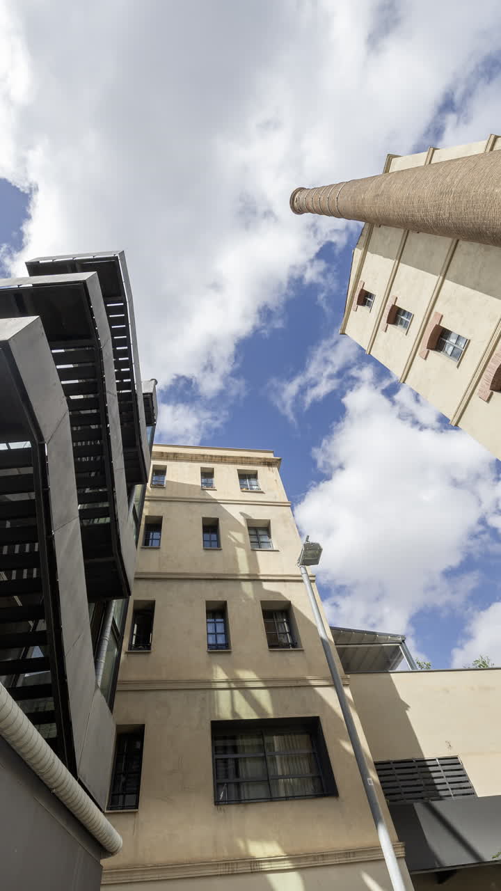 Old factory chimney and apartment buildings in barcelona in vertical