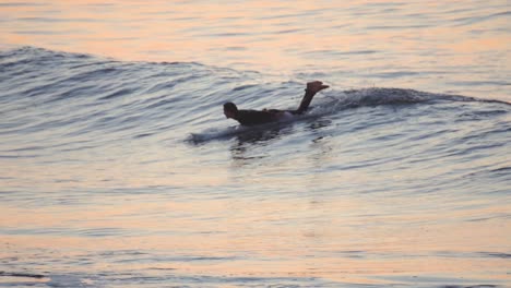 Young-person-surfing-at-sunrise-doing-tricks-on-a-wave